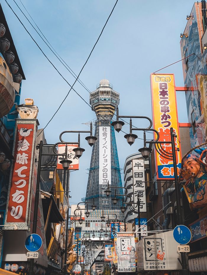 Colorful street scene in Osaka, Japan featuring Tsutenkaku Tower surrounded by vibrant signage.