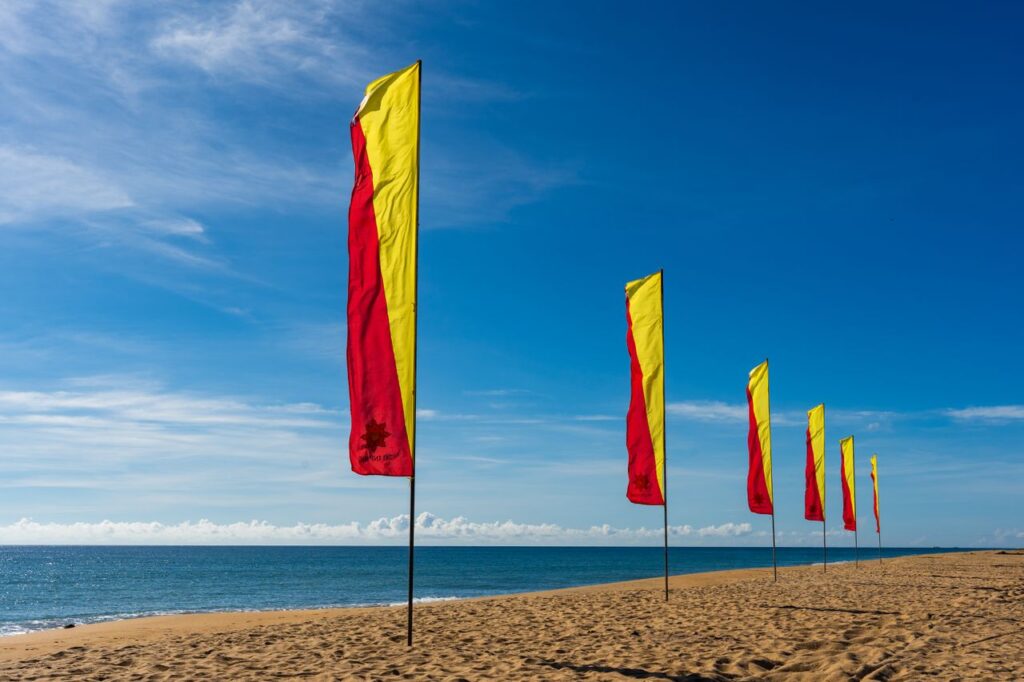 Colorful red and yellow flags flutter on Batticaloa's sunny beach, Eastern Province, Sri Lanka.