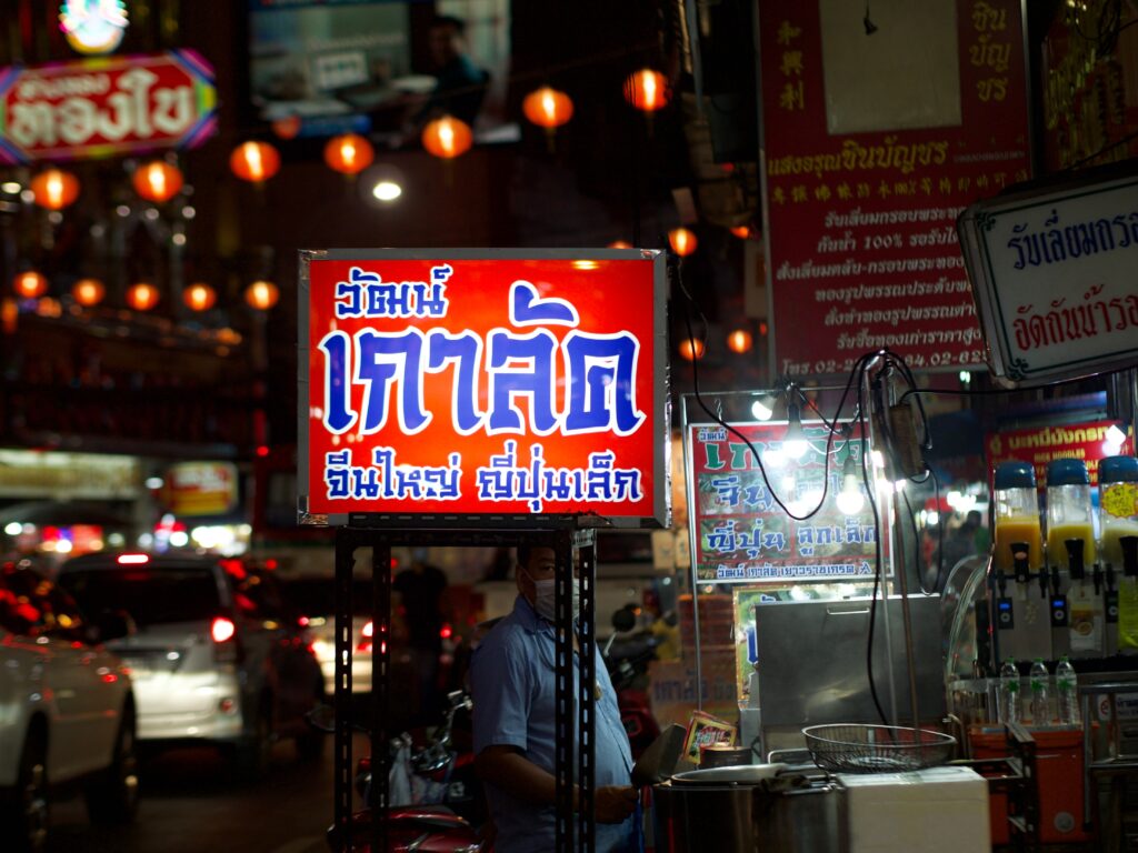 A bustling urban street at night with illuminated signs and vibrant market life.