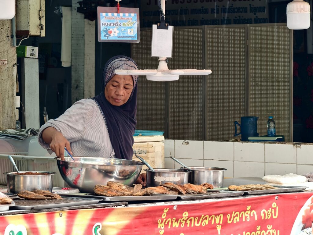 Street food vendor prepares traditional dishes in Bangkok, Thailand market.