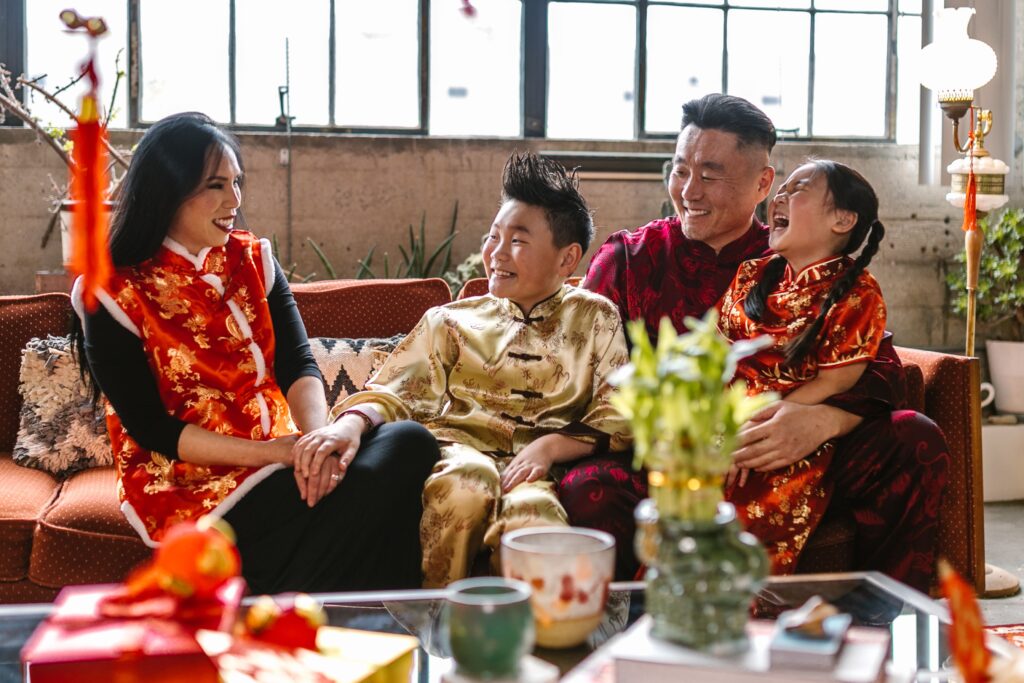 A joyful family in traditional clothing celebrating Lunar New Year in their living room.